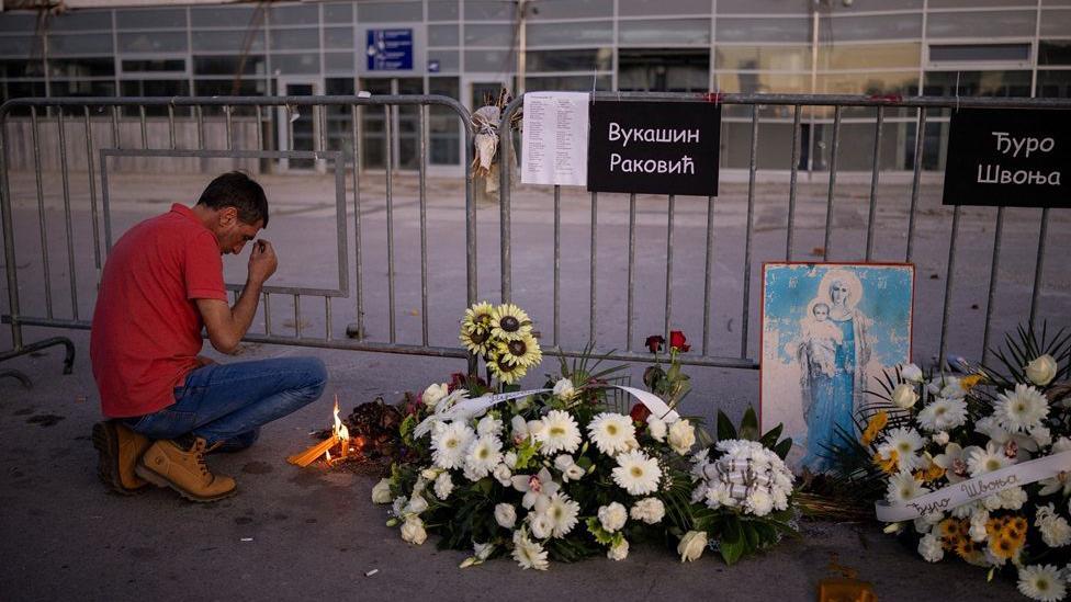 Dan žalosti u Srbiji na godišnjicu tragedije u Novom Sadu 2 Čovek se krsti ispred Železničke stanice u Novom Sadu gde je položeno cveće