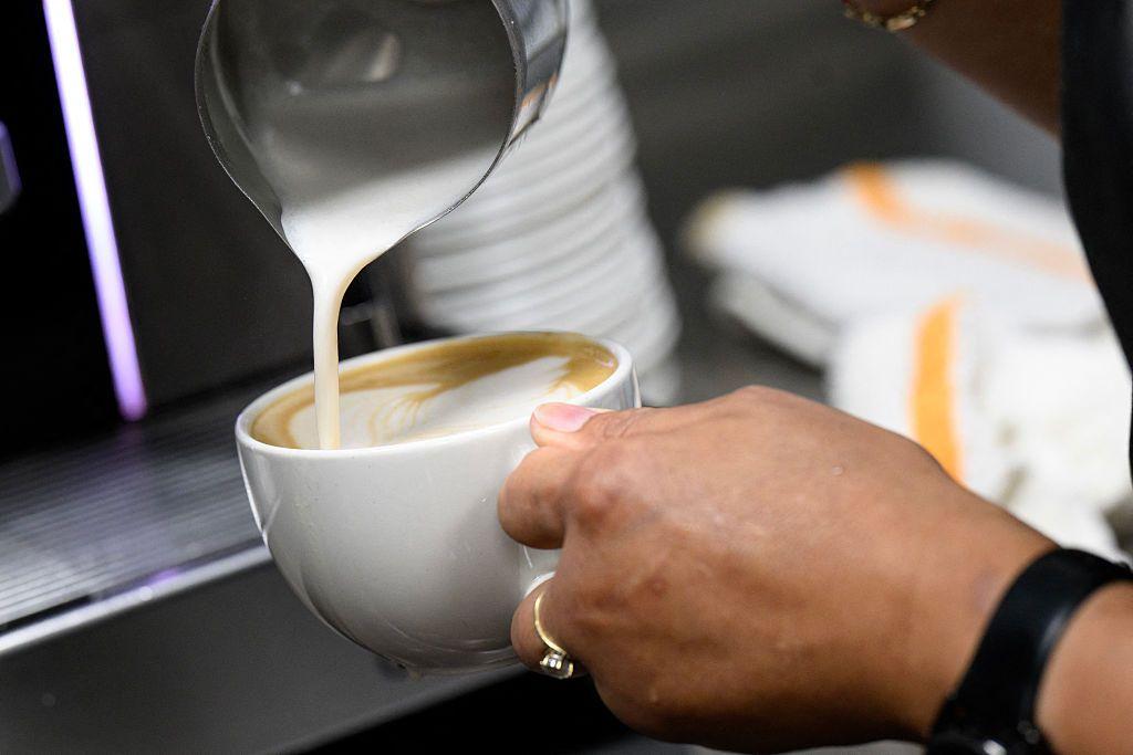 Atendente prepara café com leite num restaurante