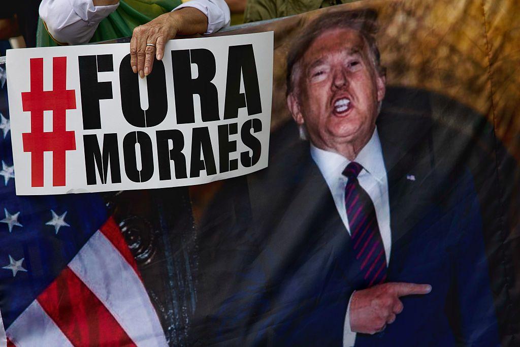 Um apoiador de Jair Bolsonaro, ex-presidente do Brasil, segura um cartaz contra o juiz do Supremo Tribunal Federal Alexandre de Moraes ao lado de uma imagem do presidente dos EUA, Donald Trump, durante um comício na Avenida Paulista, em São Paulo, Brasil, no domingo, 3 de agosto de 2025. 
