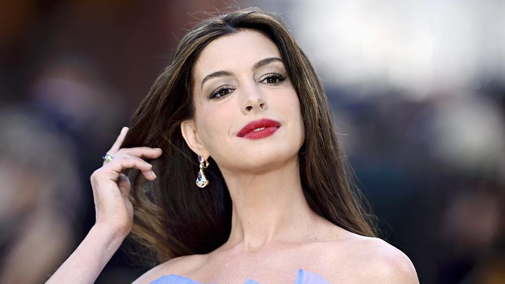 A atriz Anne Hathaway, com a m&atilde;o direita nos cabelos