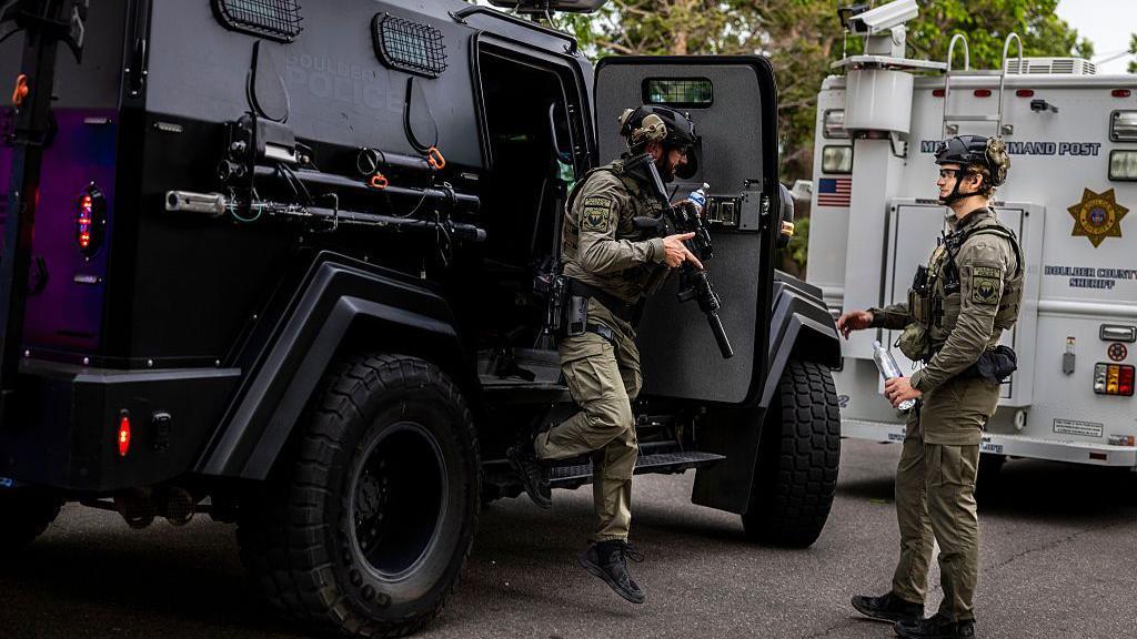 Dos policias se bajan de vehículos blindados en el lugar de los hechos