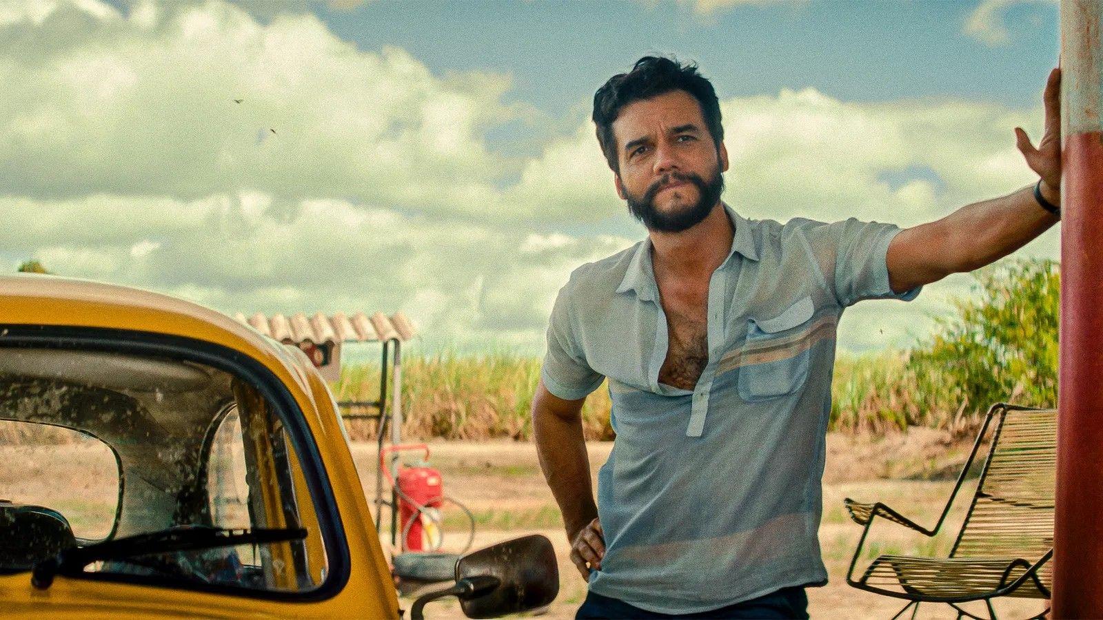 Wagner Moura apoiado em um poste