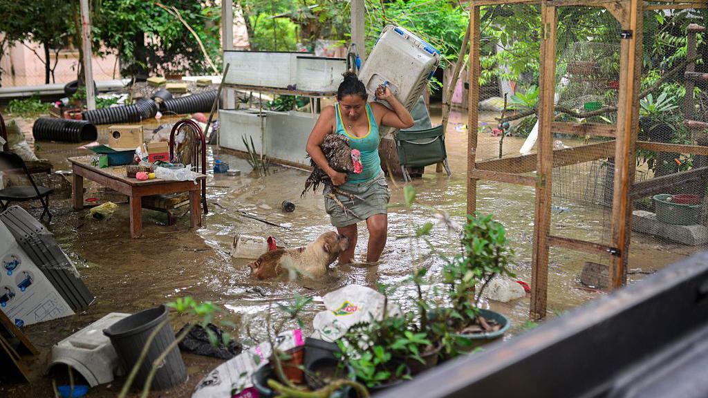 Mujer en medio de un patio dañado por las inundaciones