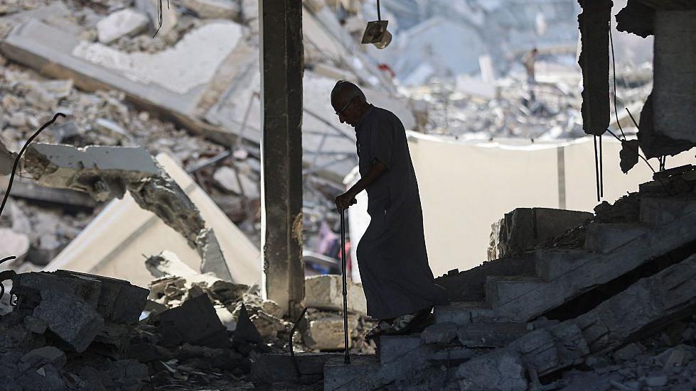 Un anciano con bastón camina entre las ruinas de la ciudad de Gaza.