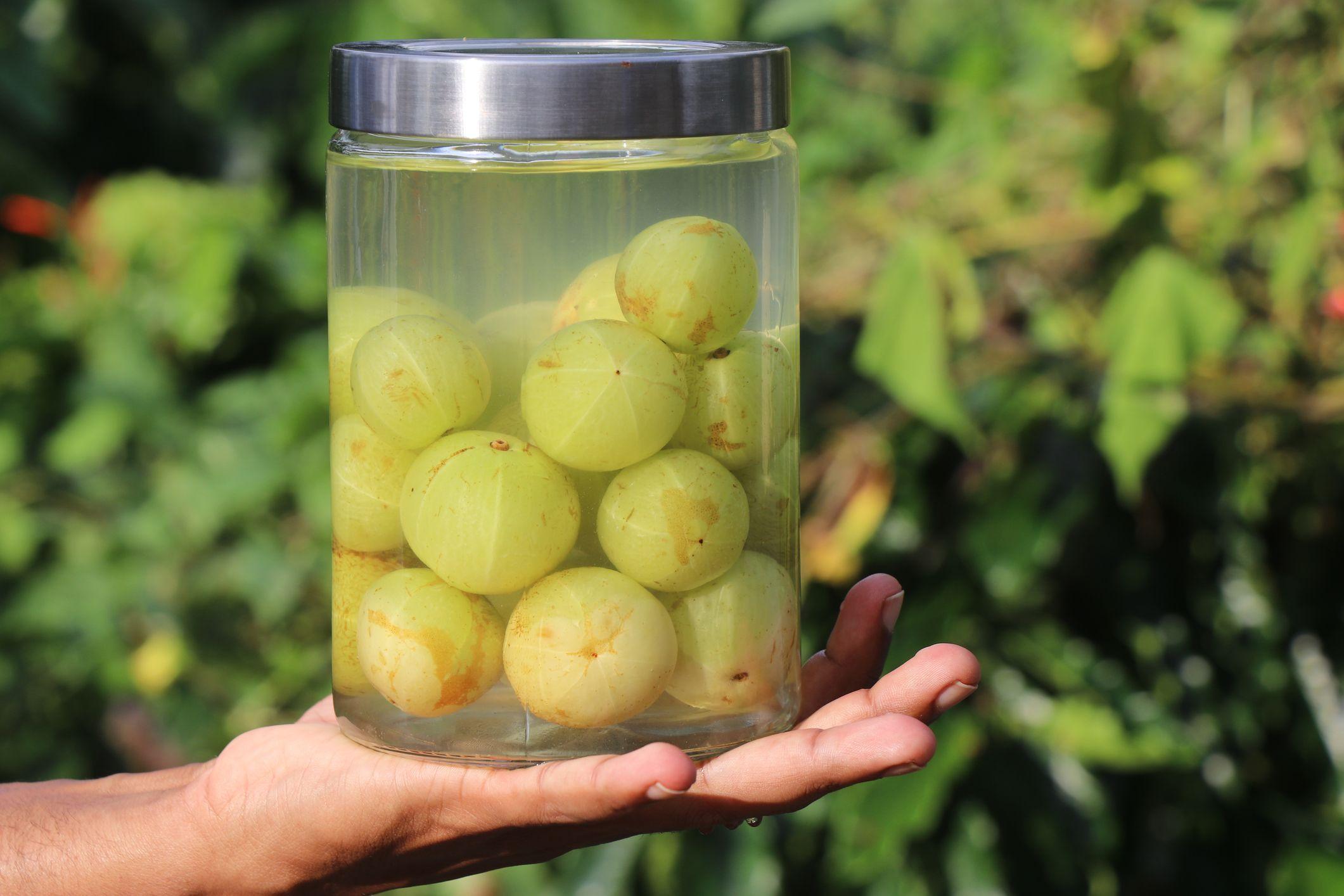 Mano sosteniendo frasco con grosellas en agua salada