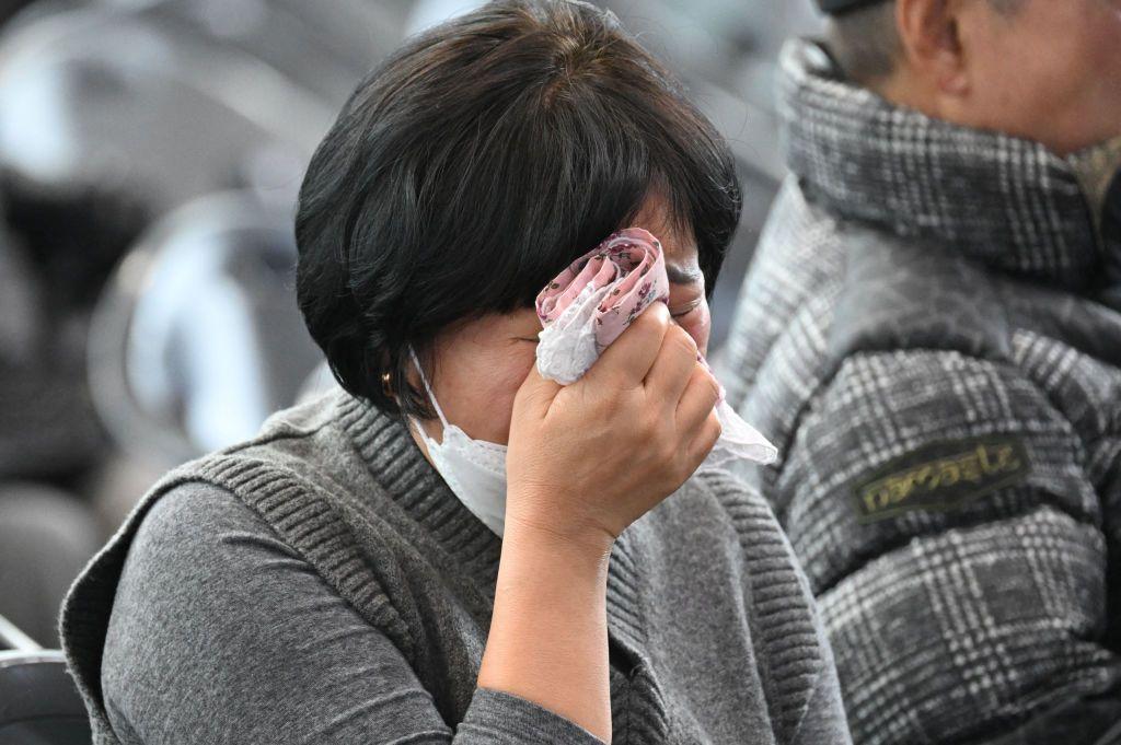 Una mujer del colectivo de familiares de víctimas del accidente de Jeju Air se seca las lágrimas con un pañuelo. 
