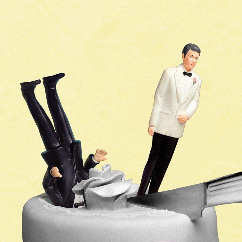 Bolo de casamento sendo cortado com uma faca, com dois bonecos masculinos, um deles com a cabeça enterrada no bolo