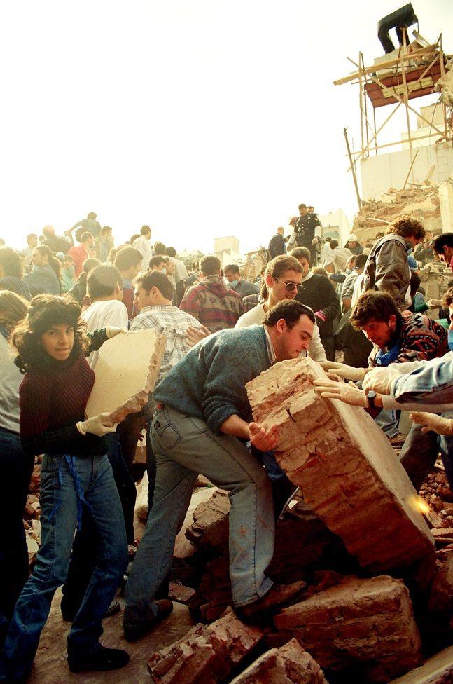 Un grupo de personas levantan pesados escombros