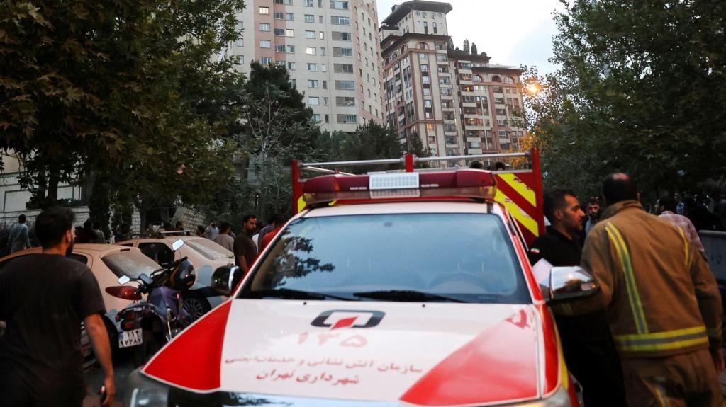 Varias personas rodean un auto de ayuda en una calle de Teherán