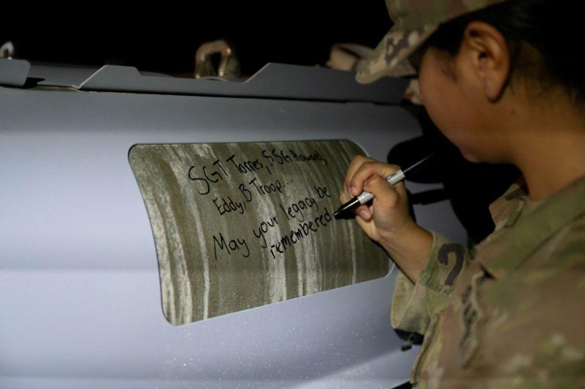 جندية أمريكية توقع أسماء القتلى الأمريكيين على أنظمة ذخيرة GBU-31 قبيل شن الجيش الأمريكي ضربات واسعة النطاق ضد العشرات من أهداف تنظيم الدولة في سوريا في رد انتقامي