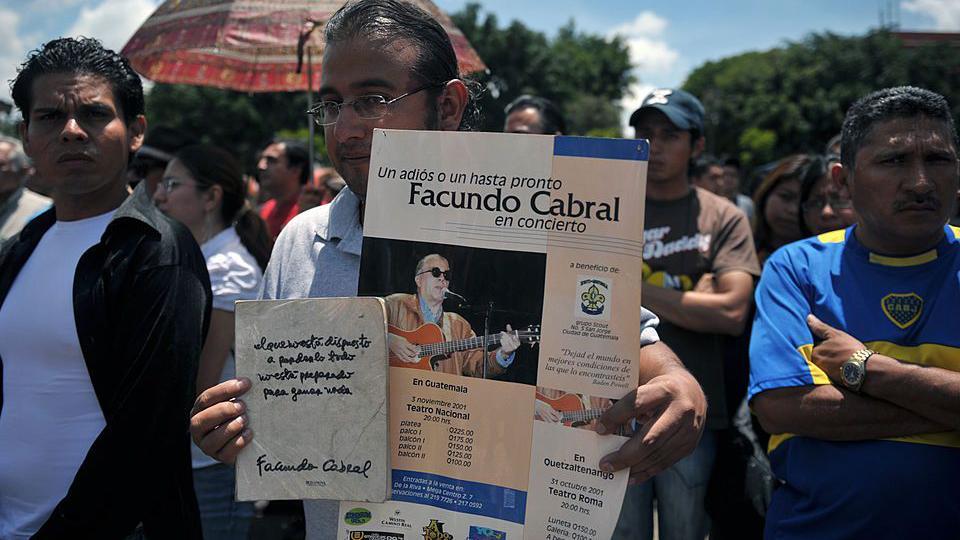 Un manifestante sostiene un cartel con la foto de Facundo Cabral y el anuncio de su concierto, durante una protesta en Guatemala