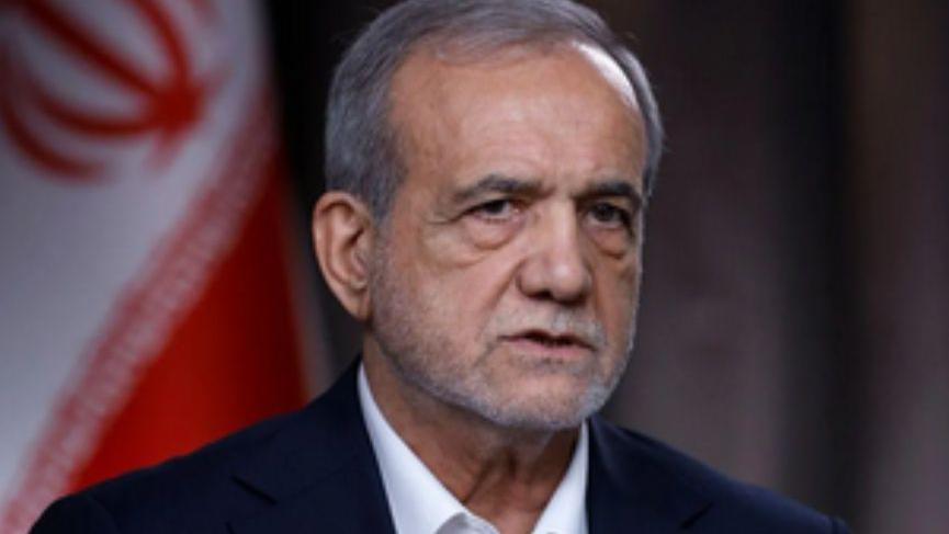 الرئيس الإيراني يرتدي بدلة سوداء وقميص أبيض وخلفه علم إيران 