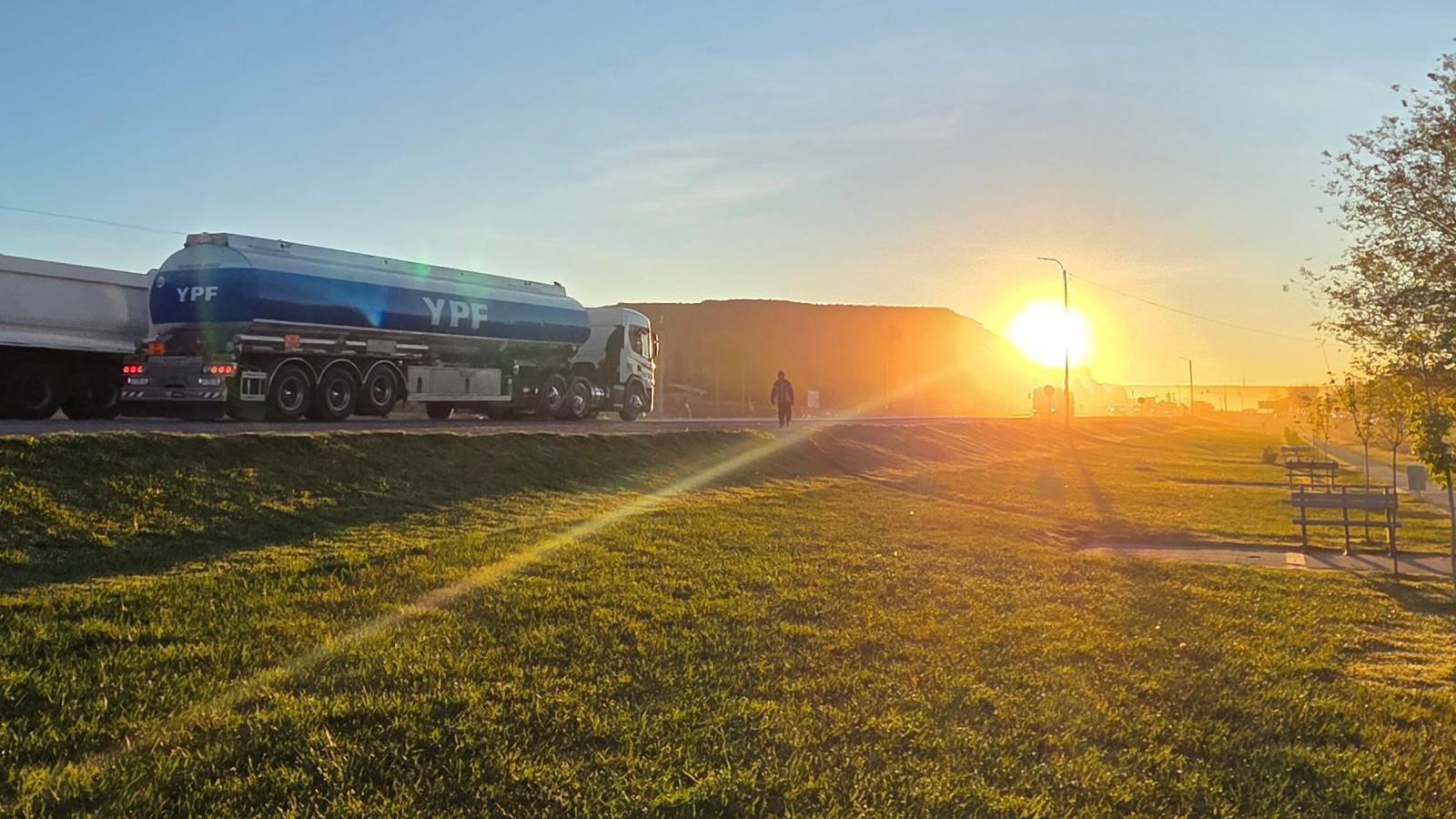 Camión con el logo de YPF viaja por una ruta al amanecer.