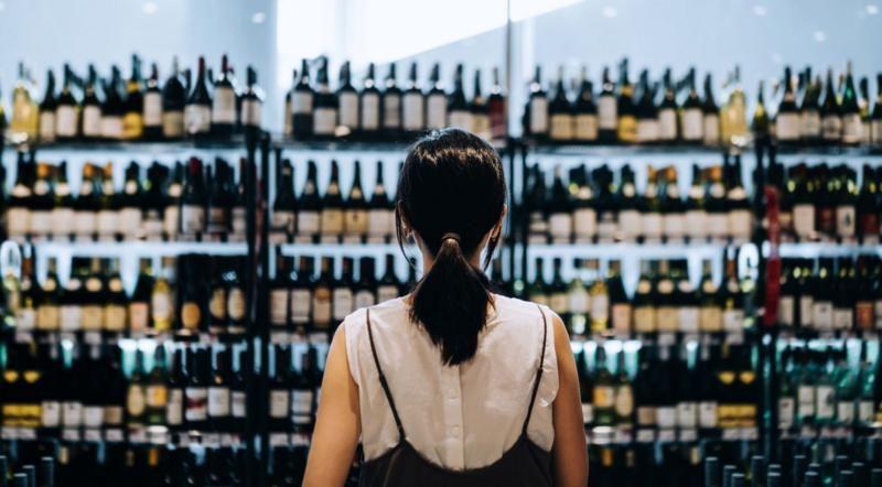 Mulher olha prateleiras de bebidas em estabelecimento
