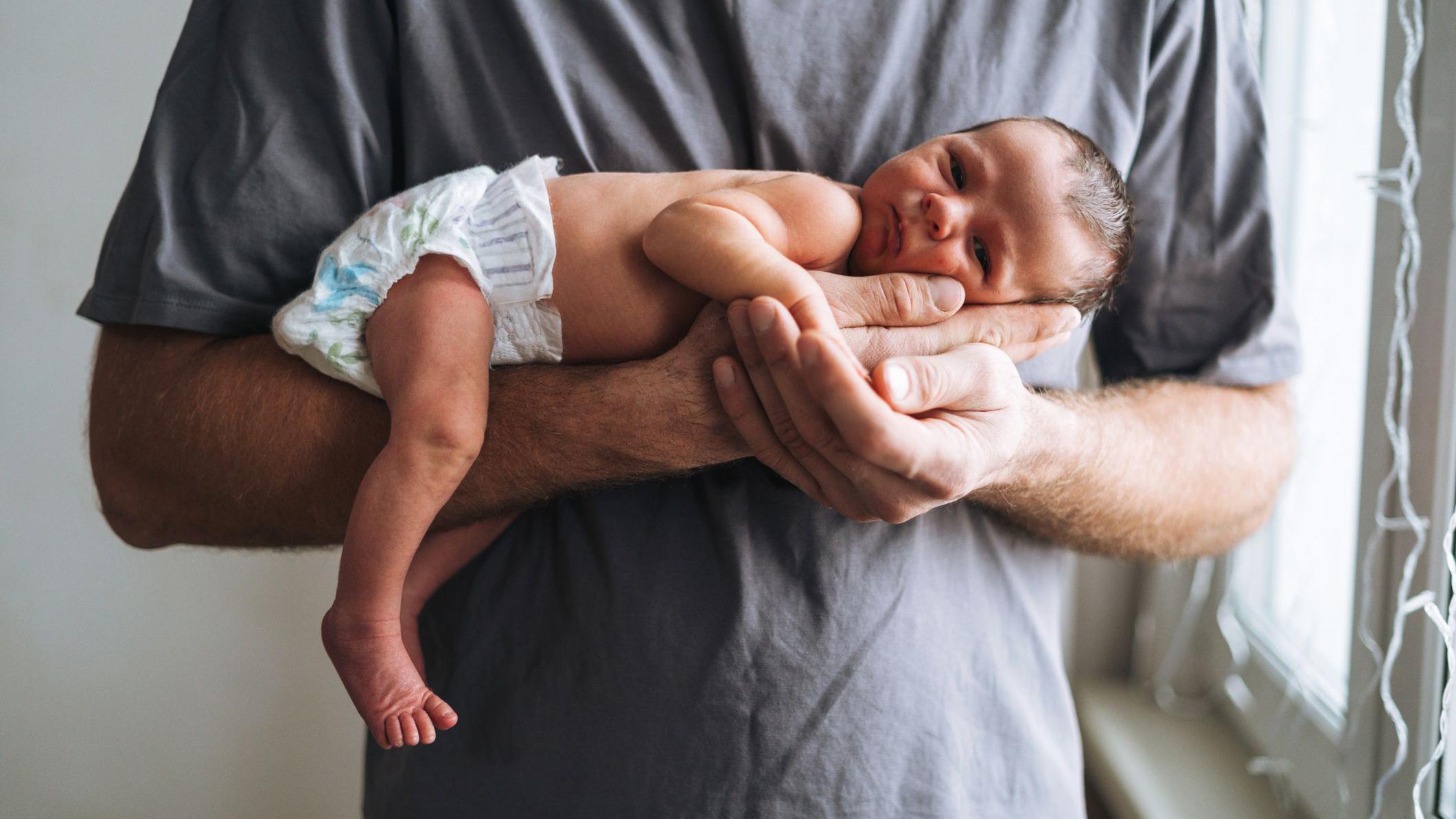 Un padre sostiene a su bebé en brazos.