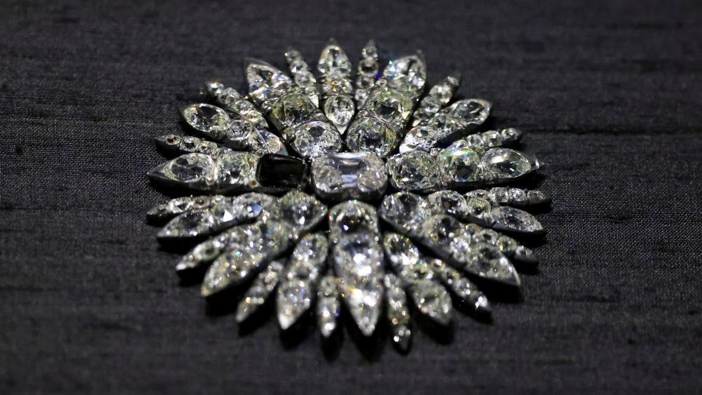 Un deslumbrante accesorio con incrustaciones de diamantes en forma de sol sobre un fondo negro. Una pieza faltante destaca en el centro del artículo.
