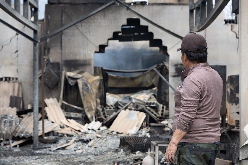 한 남성이 산불로 전소된 사과 창고를 바라보고 있다