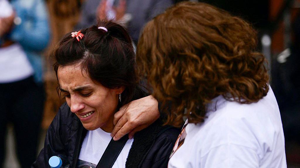 Duas mulheres chorando em meio a uma manifestação