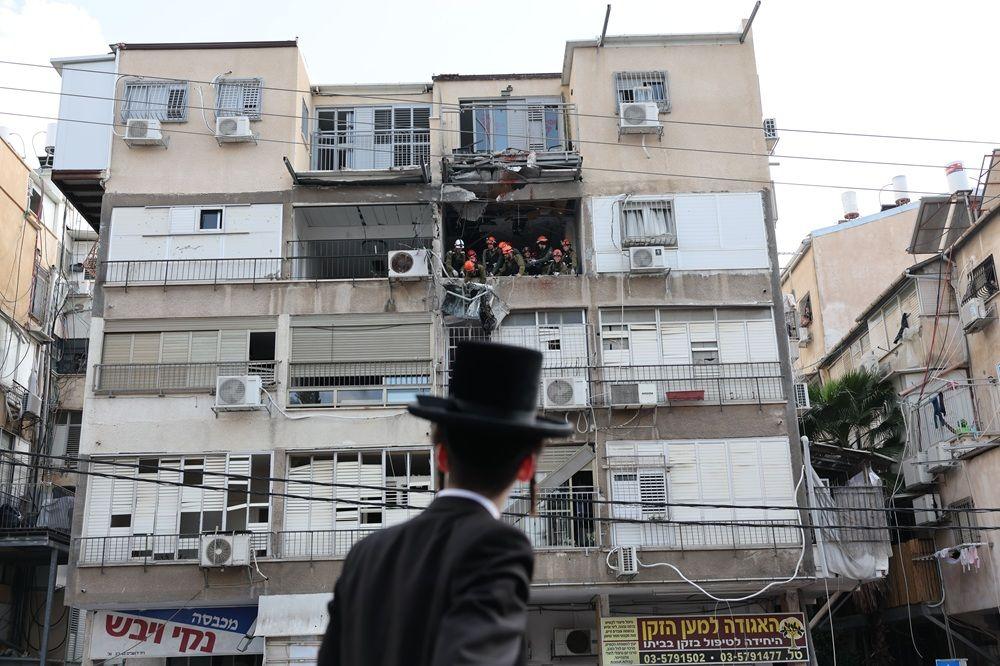 čovek gleda u zgradu pogođenu u iranskom napadu