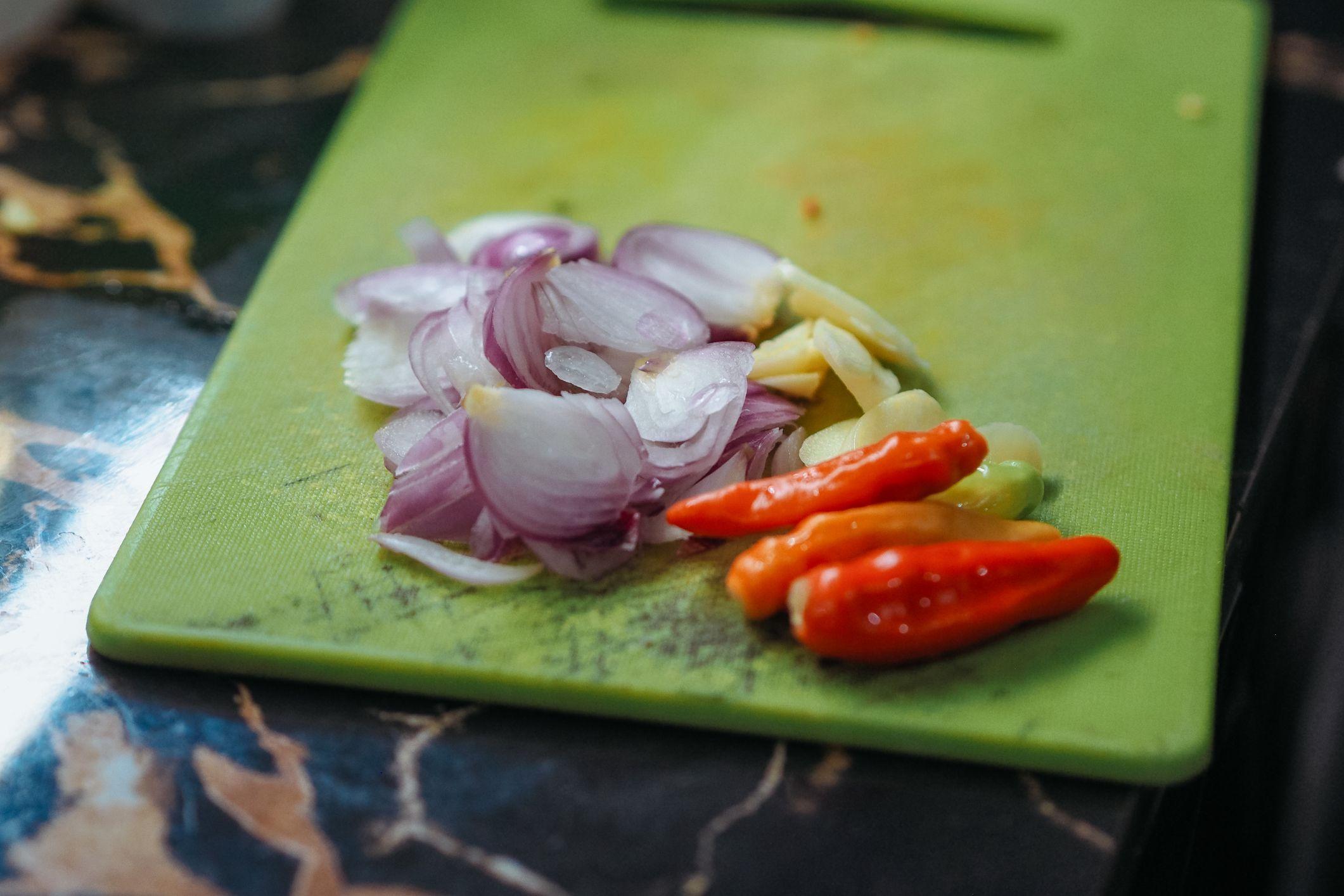 Jalapeños y cebollas en una tabla de picar verde de plástico.