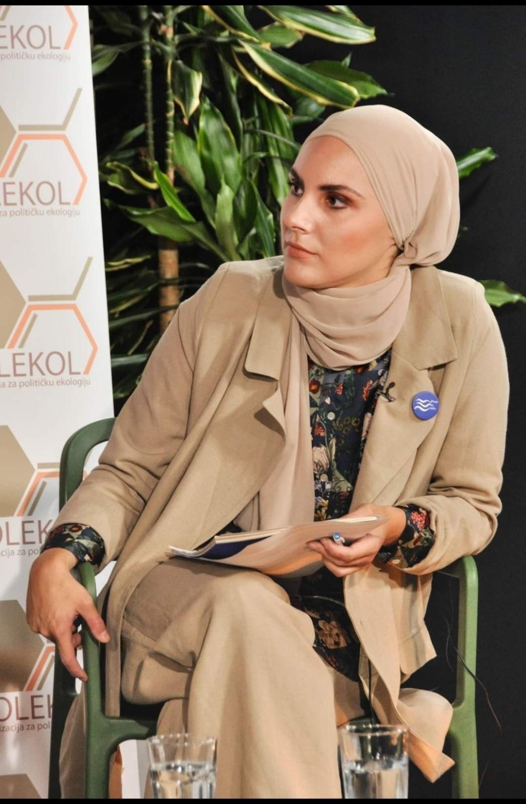 Devojka prekrivene glave sedi za govornicom