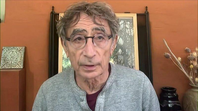 Un hombre con un jersey gris y gafas habla a una cámara