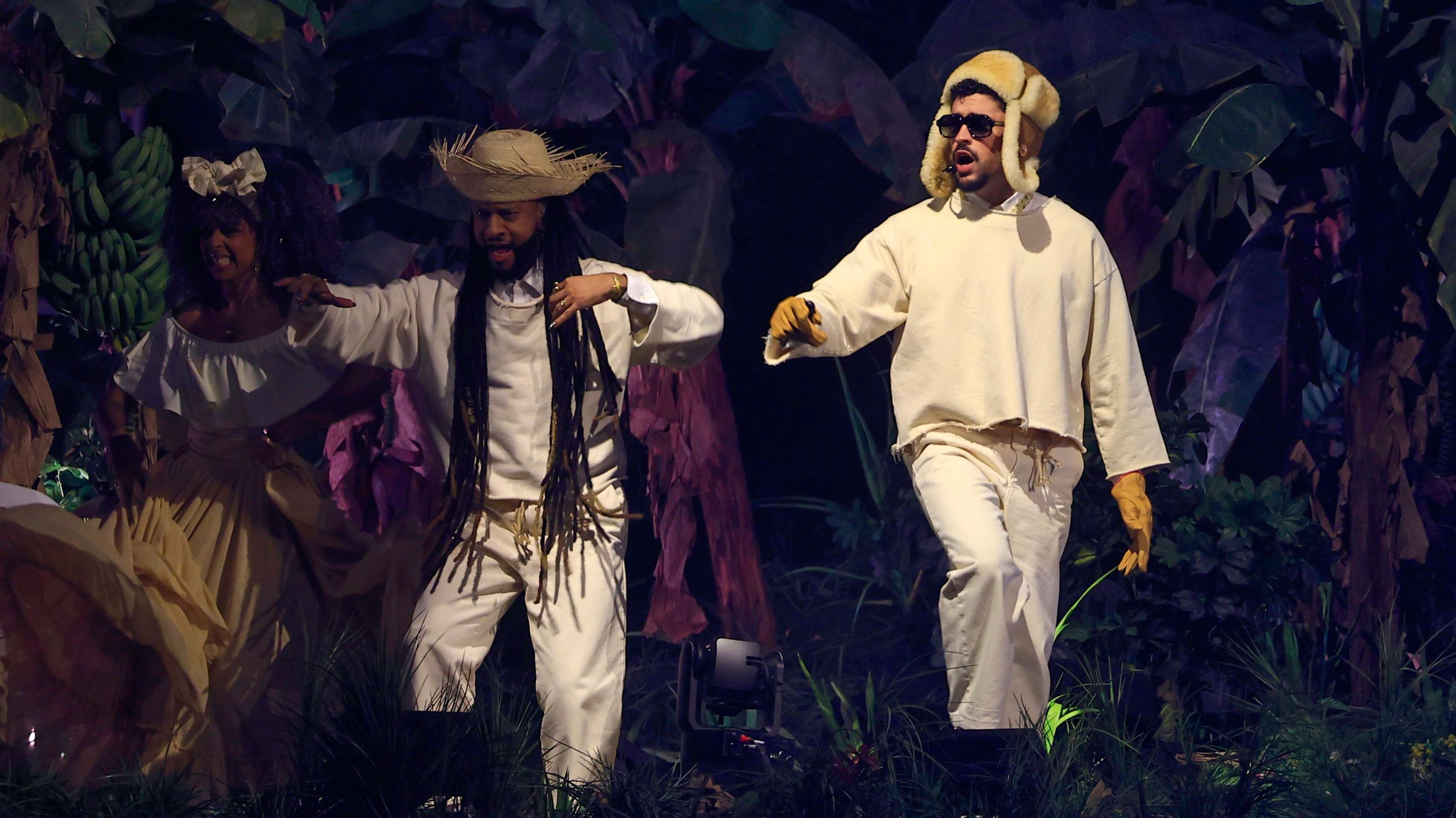 Bad Bunny junto a dos artistas que lo acompañan en el escenario.