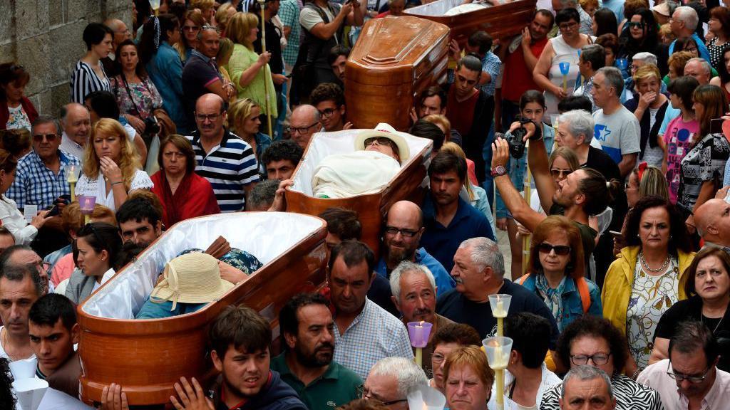 Personas llevan a hombros féretros durante la procesión de Santa Marta de Ribarteme en 2019.