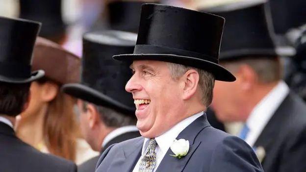 Andrew in a top hat and grey suit, laughing. Other men with top hats are beside him and a woman with a brown hat and long brown hair is in the background.