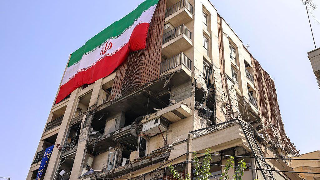Edificio residencial con una gran bandera iraní, alcanzado por un ataque israelí en Teherán el 25 de junio de 2025. 