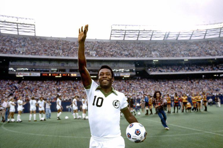 Pelé em um estádio de futebol, saudando a torcida, vestindo o uniforme do Cosmos de Nova York