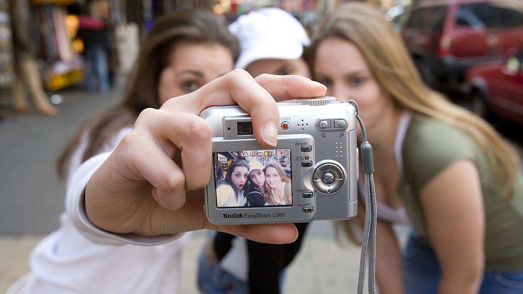 Tres adolescentes se autorretratan con una cámara digital Kodak EasyShare en Times Square.