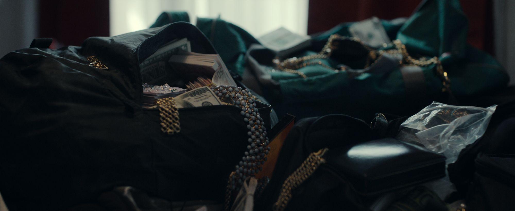 Bolsos abiertos llenos de fajos de billetes, joyas y cadenas