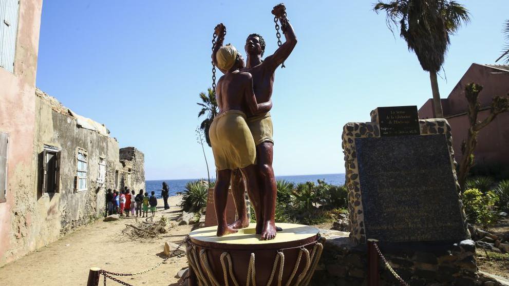 Est&aacute;tua de homem e mulher em correntes na ilha de Goree, no Senegal. O local &eacute; conhecido como a 'Ilha da Vergonha', por ter sido um grande entreposto do com&eacute;rcio transatl&acirc;ntico de pessoas escravizadas, entre os s&eacute;culos 15 e 19.