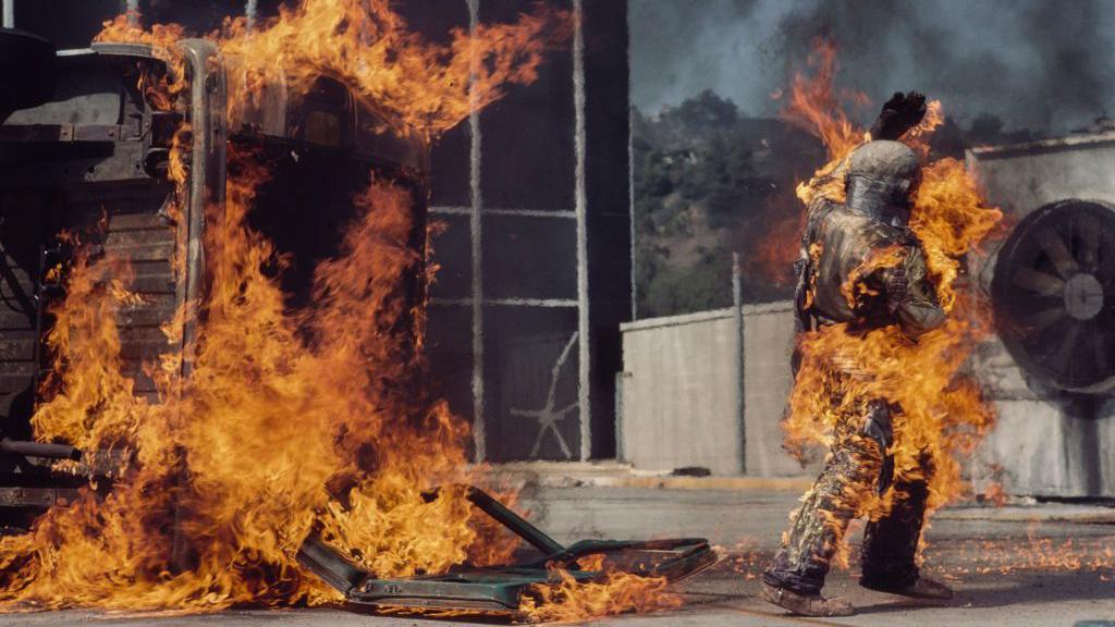 一張照片顯示基蒂·奧尼爾在其中一場特技表演中，走過一片被火焰吞噬的場地（8/11/1977）