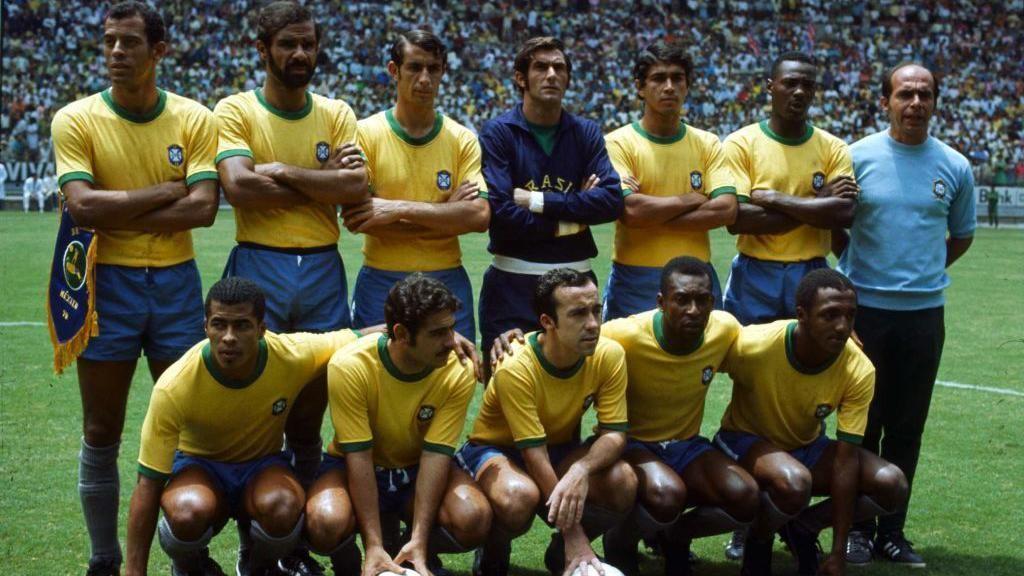 منتخب البرازيل في كأس العالم  عام 1970 في الملعب ويرتدون قمصان صفراء أكمامها قصيرة.