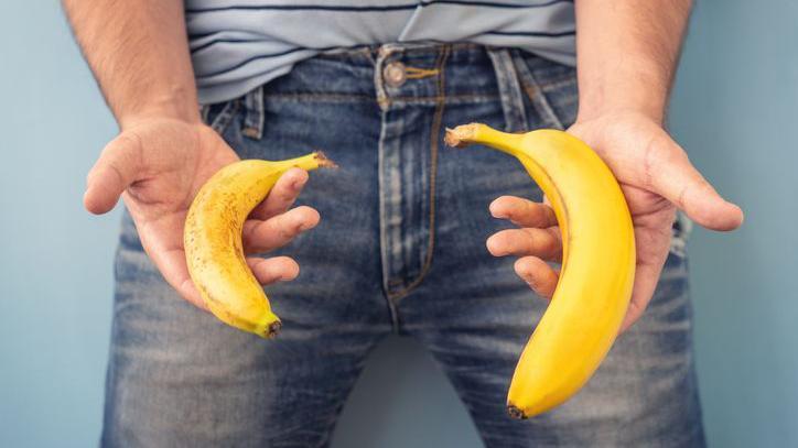 Homem segurando bananas de dois tamanhos diferentes