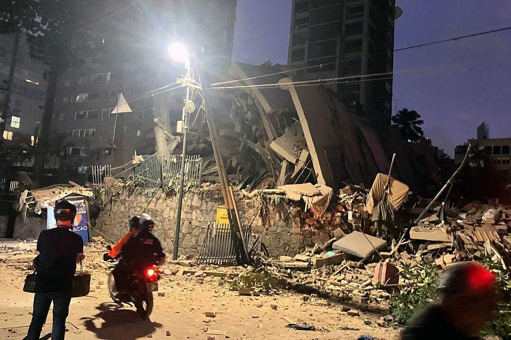 Un edificio colapsado en la ciudad de Caracas mientras una moto pasa por el frente