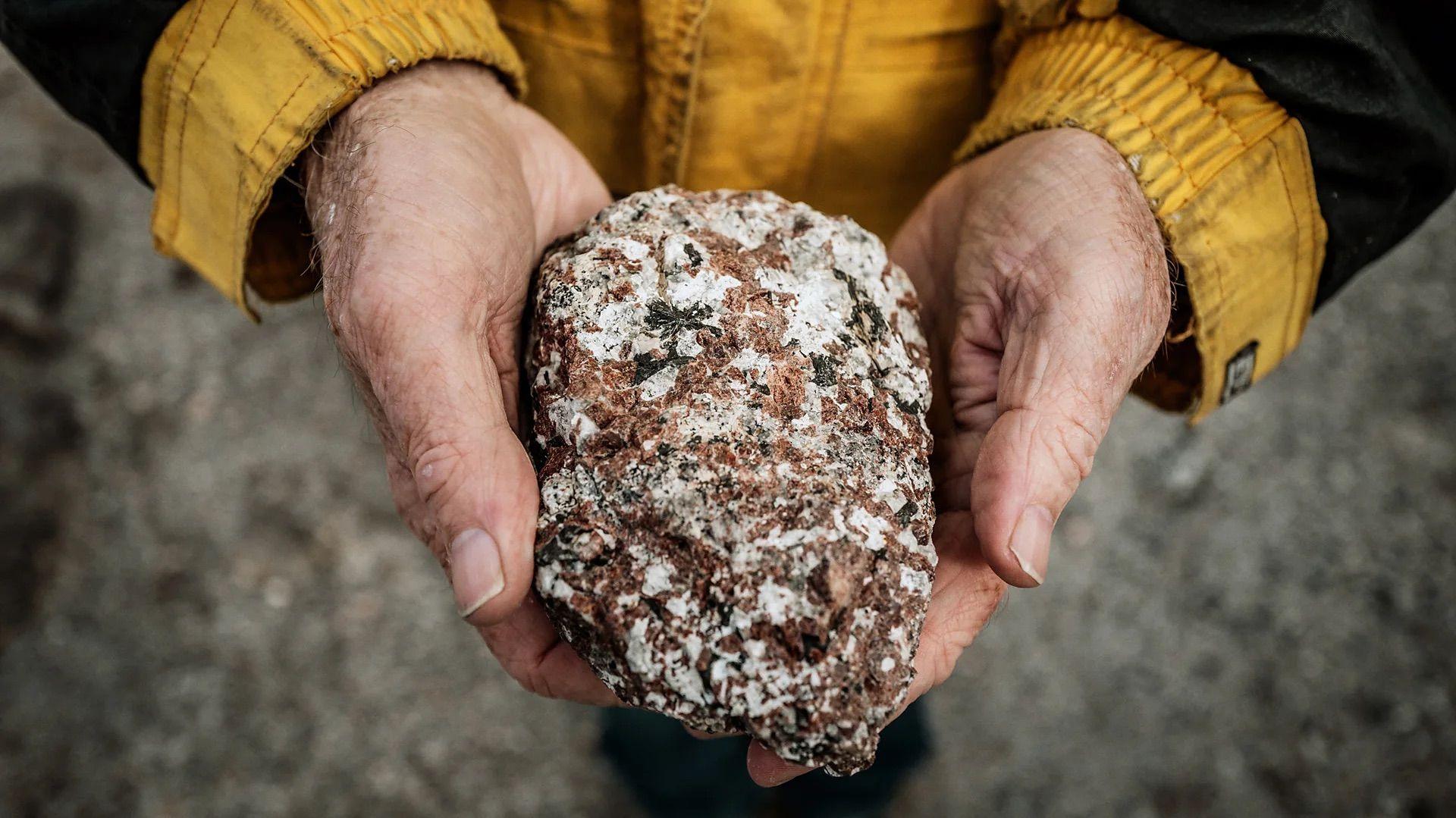一雙人手捧著一塊稀土礦石