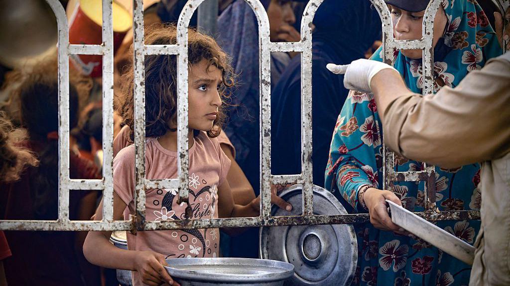 Una niña espera por alimentos en un centro de distrubución en Gaza