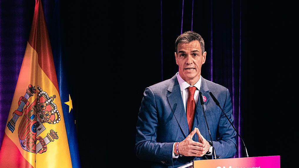 El presidente de gobierno español, Pedro Sánchez, en medio de una tarima con las banderas de España y la Unión Europea. 