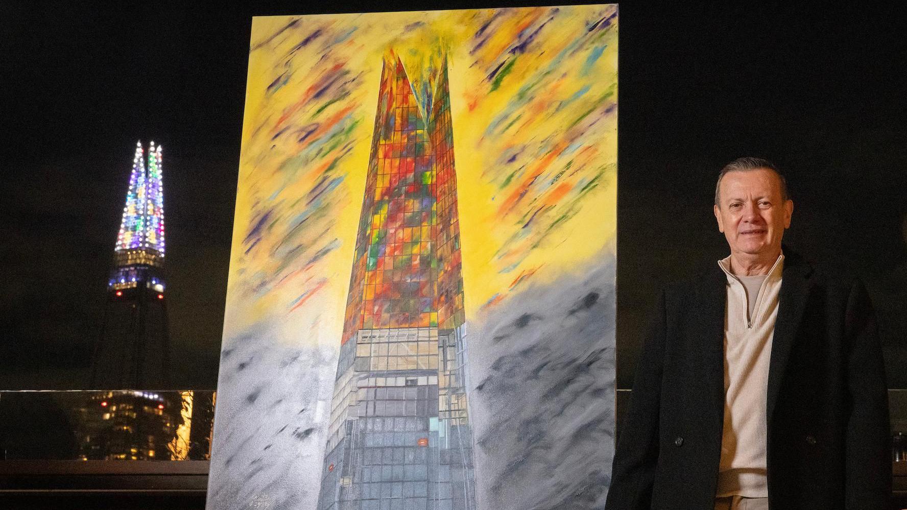 El pintor colombiano Gustavo Zuluaga posa junto a su pintura "Luces de Navidad" y en el fondo se ve el edificio The Shard, en Londres. 