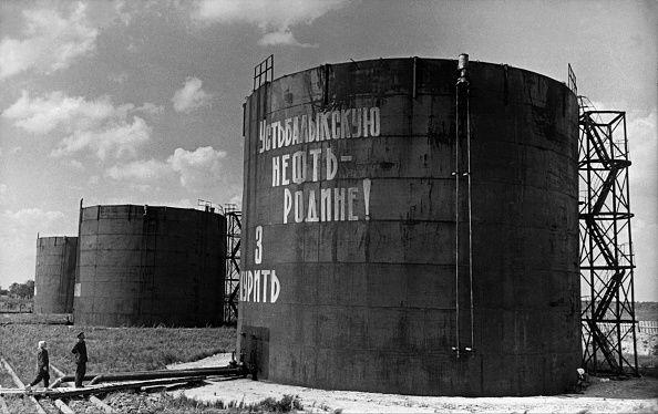 A black-and-white photograph shows two people reading the slogan 