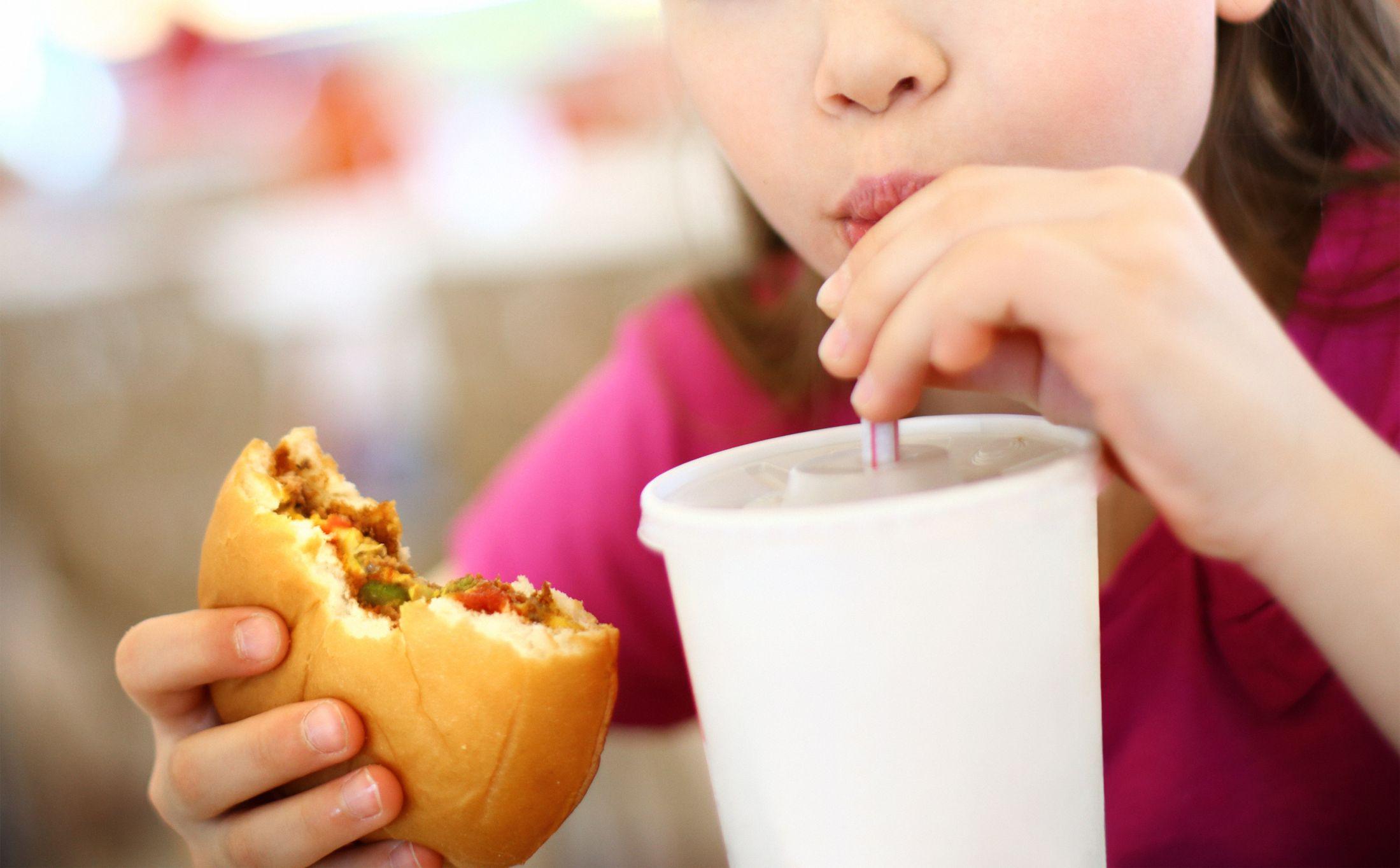 una niña comiendo hamburguesa bebiendo y refresco