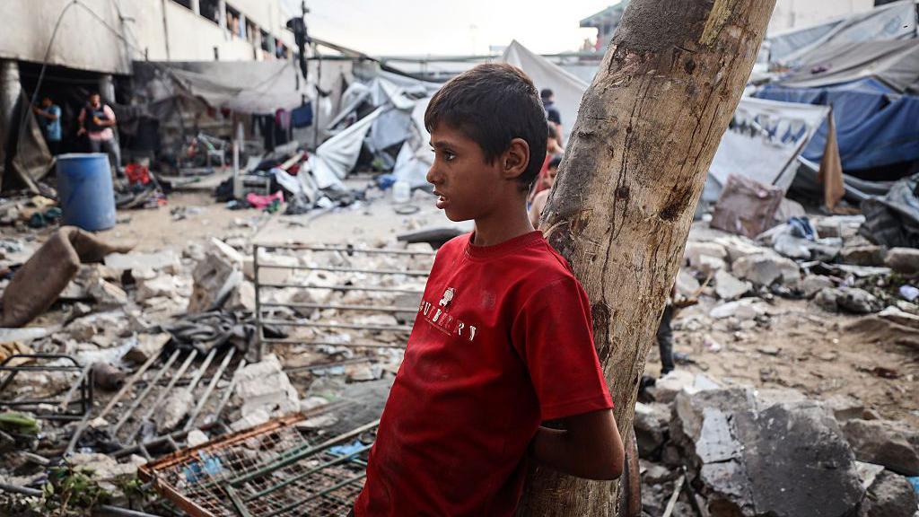 "أسوأ من البدء من الصفر": ما حجم مهمة إعادة إعمار غزة؟ 9 طفل فلسطيني يقف حزيناً يشاهد الأضرار التي لحقت بمدرسة الفارابي، التي تحولت إلى ملجأ بعد تعرضها لغارة إسرائيلية، في مدينة غزة، في 7 سبتمبر/أيلول 2025.