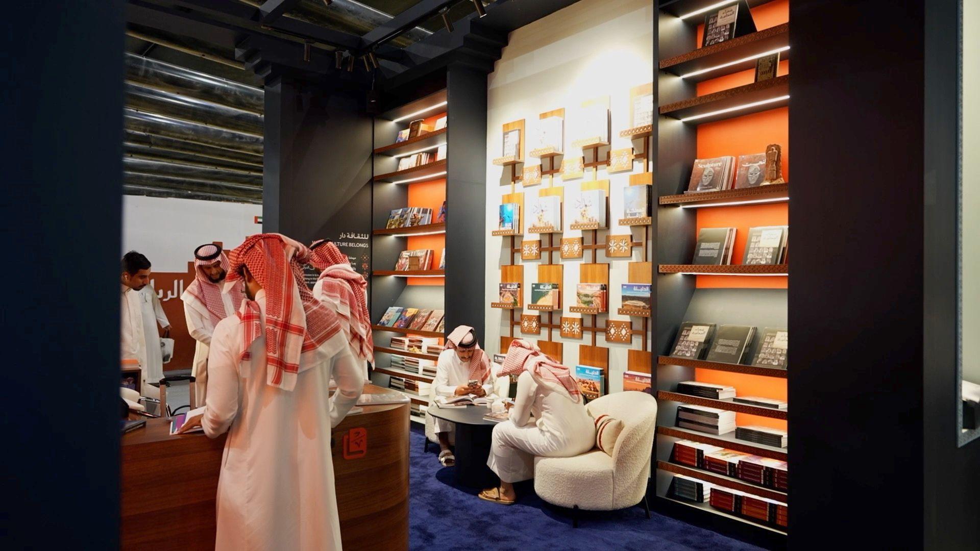 بين الانفتاح والرقابة: معرض الرياض للكتاب يكشف ملامح التحوّل الثقافي السعودي 6 صورة تُظهر رجالاً يرتدون جلاليب بيضاء، بينما يرتدي بعضهم عقالاً، ويتصفحون بعض الكتب المعروضة في المعرض، وتحيط بهم أرفف وُضعت عليها كتب.