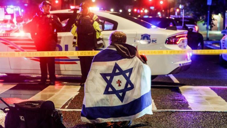 Una persona con una bandera de Israel cerca del cordón policial donde ocurrió el ataque.