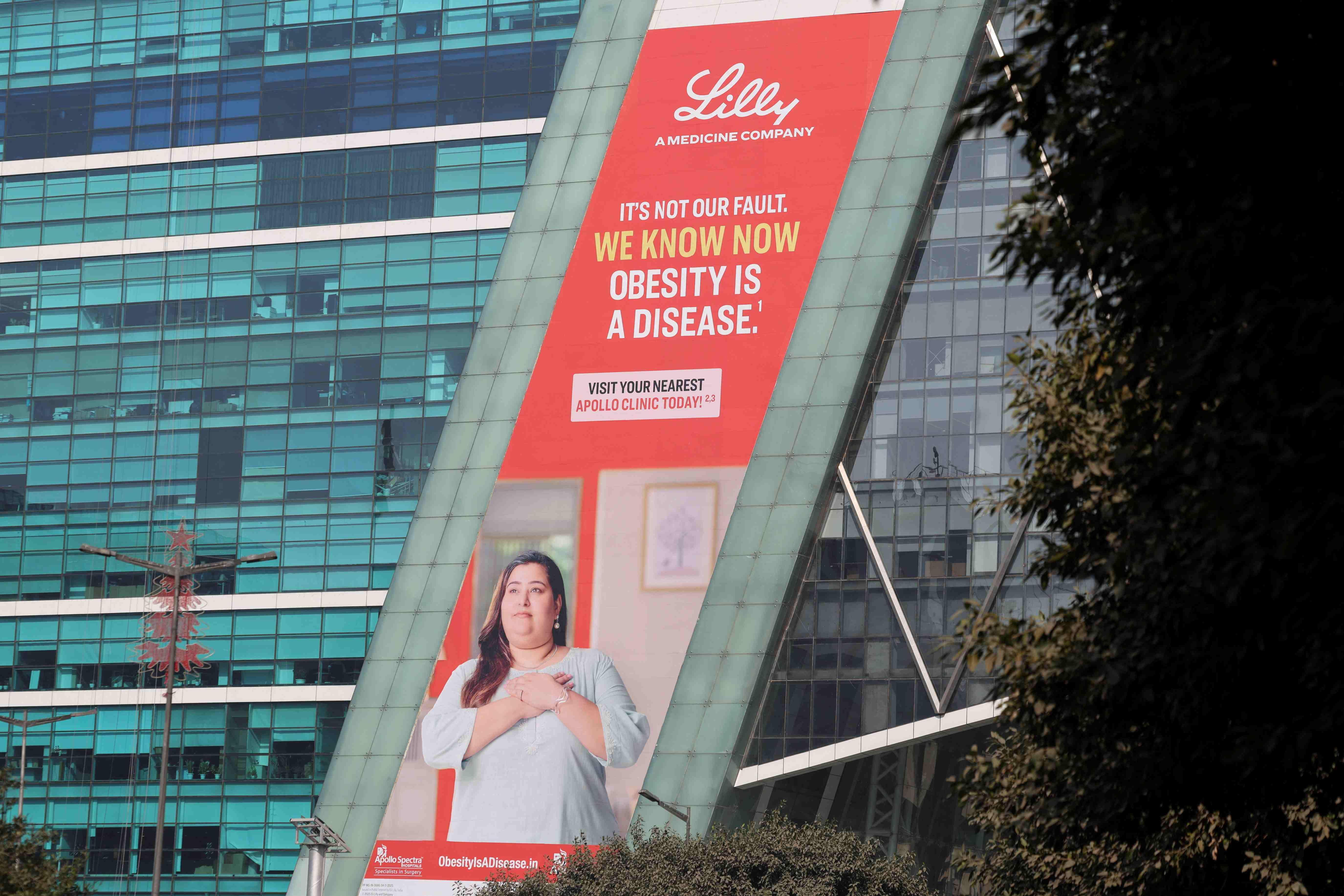 Um outdoor da farmac&ecirc;utica Eli Lilly em um pr&eacute;dio em Gurugram (&Iacute;ndia) mostra uma mulher vestindo uma t&uacute;nica, com as m&atilde;os sobre o peito. O slogan diz: &ldquo;N&atilde;o &eacute; nossa culpa. Agora sabemos que a obesidade &eacute; uma doen&ccedil;a
