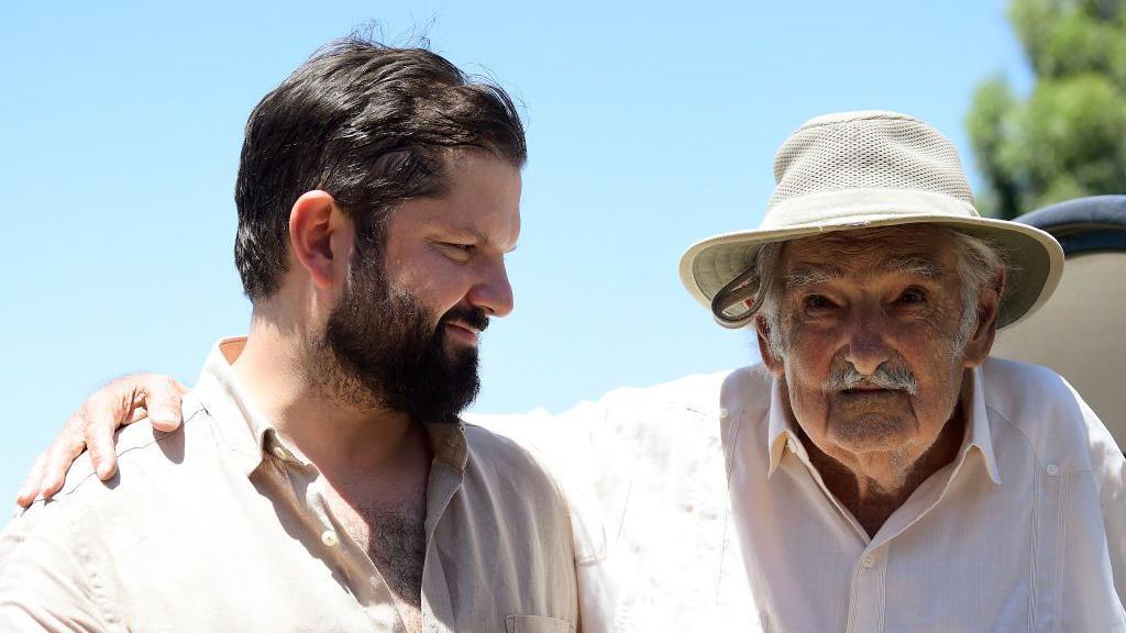 El presidente de Chile, Gabriel Boric, junto al expresidente de Uruguay José Mujica tras plantar un olivo en la casa del uruguayo.