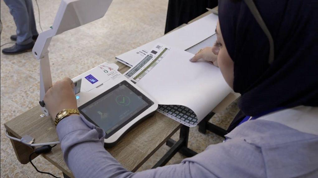 سيدة في لجنة الانتخابات في العراق تتحقق من هوية مقترع.